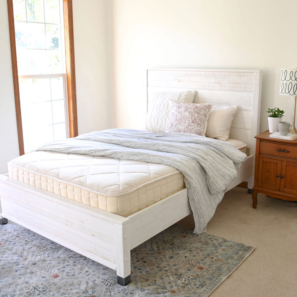 Naturepedic Serenade Organic Mattress on a bed frame in a bedroom, hero shot.