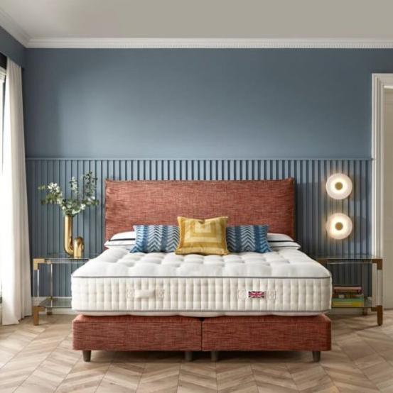 Harrison Spinks Northumberland mattress in styled room with blue walls and a maroon base and headboard.