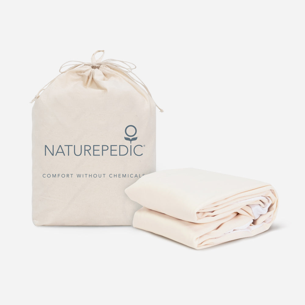 Naturepedic Organic Waterproof Mattress Protector in Naturepedic bag with stacked sheets on side 
